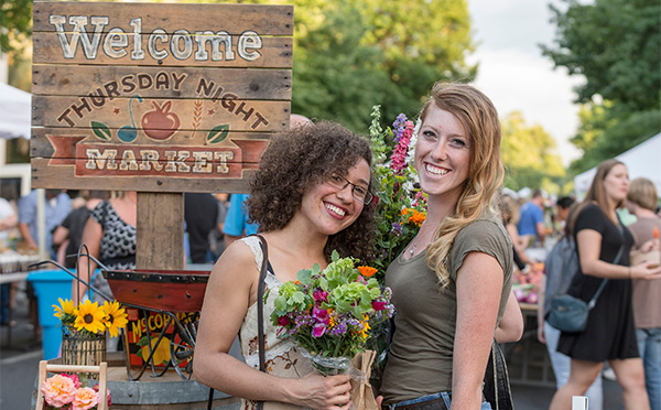 Smiling students holding bouquet of beautiful flowers at farmers market