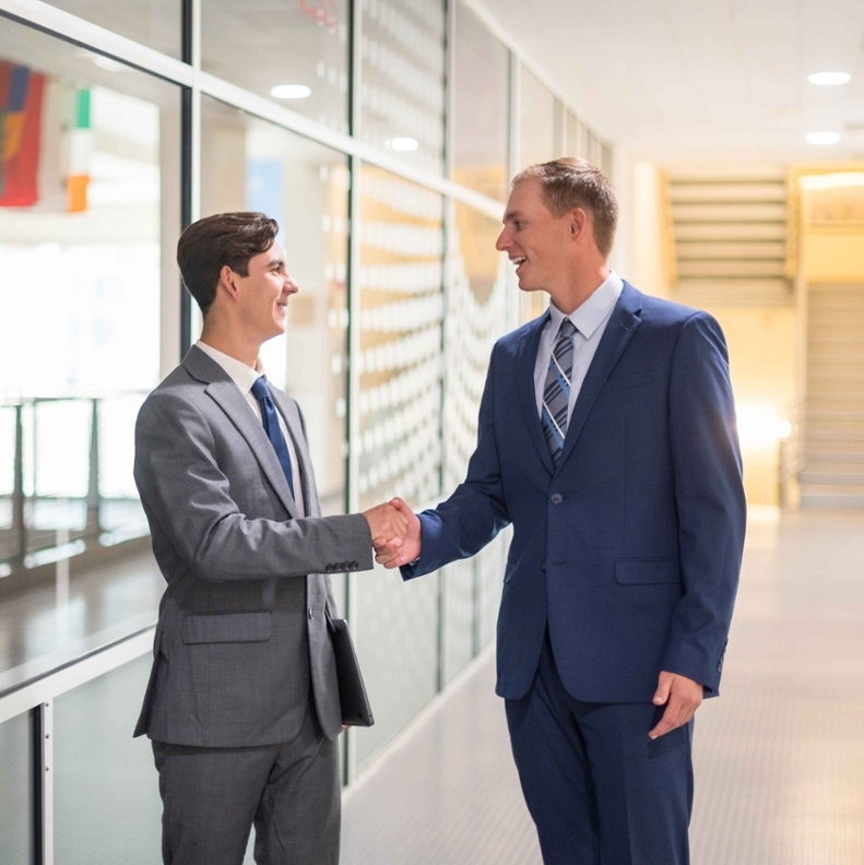 two students in business suits shaking hands