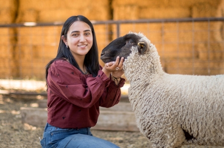 Student poses with lamb at sheep unit.