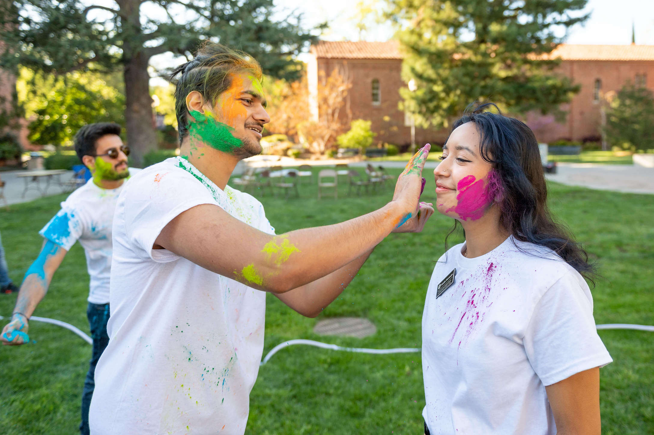 Student putting colors on another student's face for the Holi Celebration, also known as the Festival of Colors.