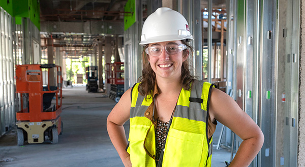 Female CM student wearing hard hat during tour of building construction