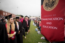 Students Standing Next to CME Banner at Commencement