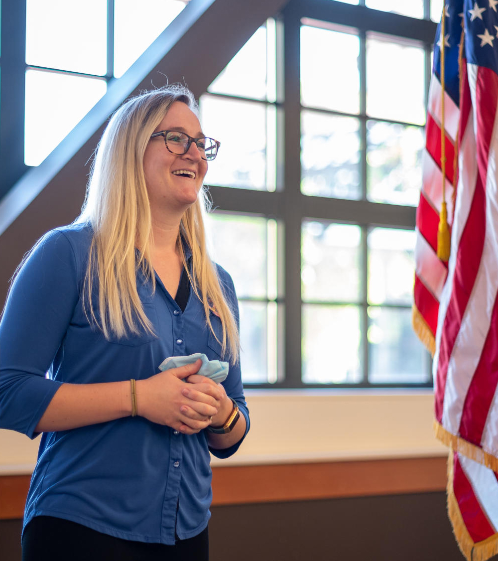 A student vet speaks at an event with the American flag behind her