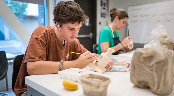 Students work in a ceramics class on projects with clay.