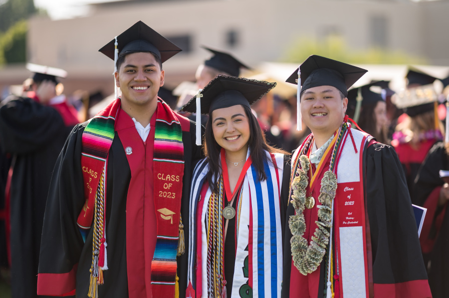 Three Chico State graduating students wearing commencement regalia
