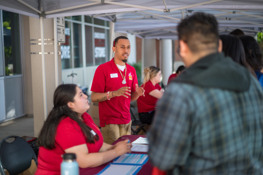 Two orientation staff members talk with a parent.