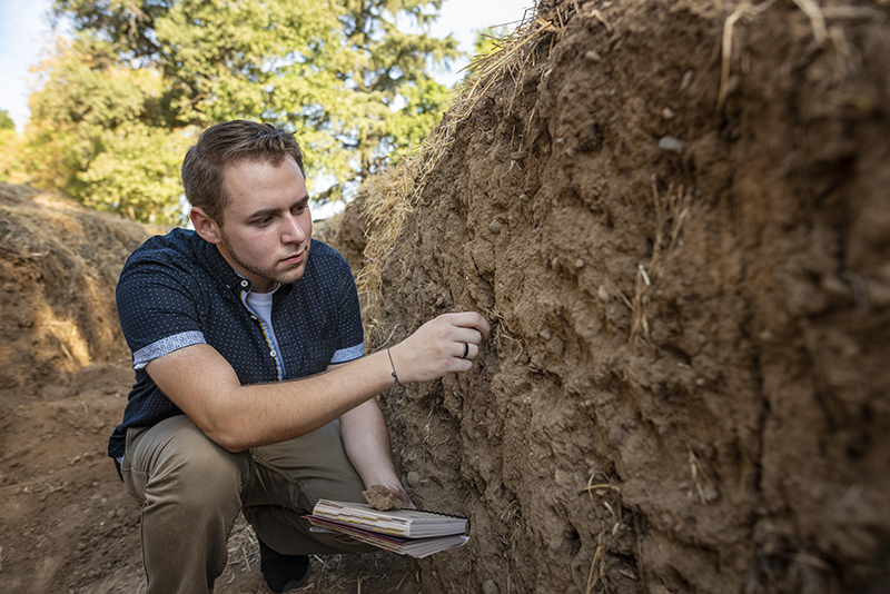 Undergraduate research assistant Seth Myrick examines the soil.