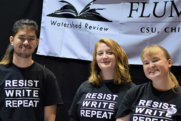 Three people smiling in front of a banner for the Watershed Review. 