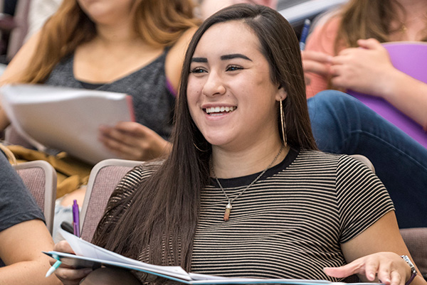 Student smiling, holding a notebook.