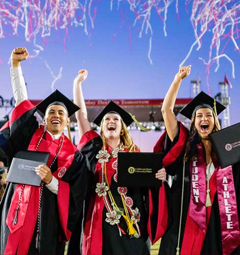 2022 Commencement graduates celebrate with raised hands while streamers fly