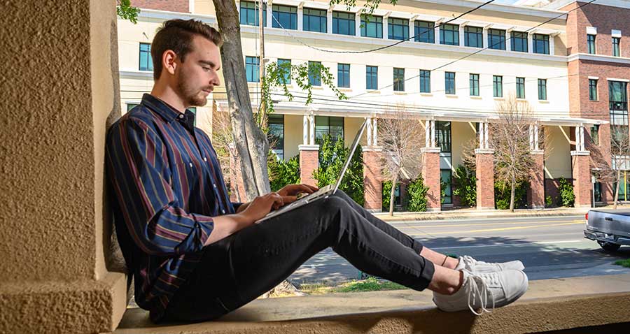 student in casual setting using laptop