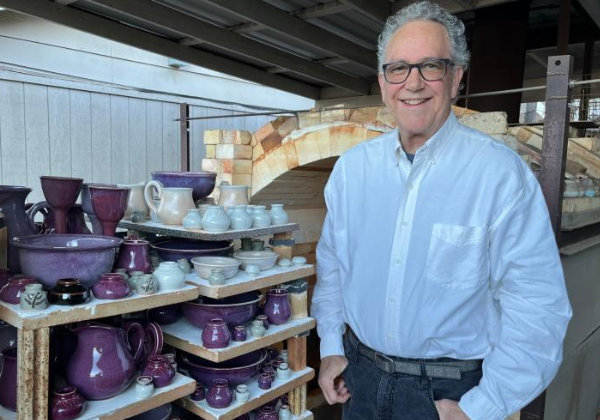 Doug Leiker standing infront of a kiln and pottery
