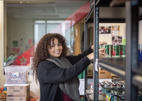 Jessica Ramirez adding cans to food pantry shelves.