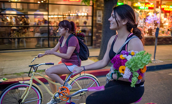 Students holding vibrantly color bouquets of flows while riding bikes home from the market