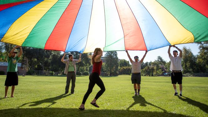 Students learn to facilitate recreation activities with a large colorful parachute