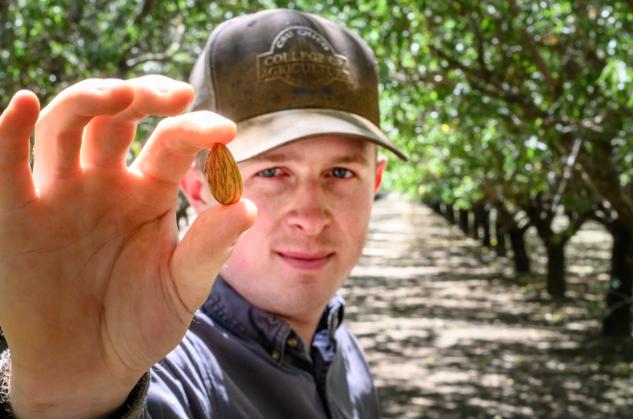 Student holding almond in the orchard