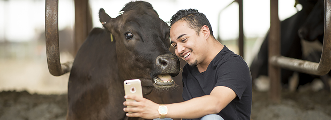 Student smiles for a selfie with a dairy cow