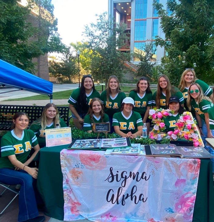 15 sorority members grouped together with two holding a sign that reads 'Sweet Home Signma Alpha'
