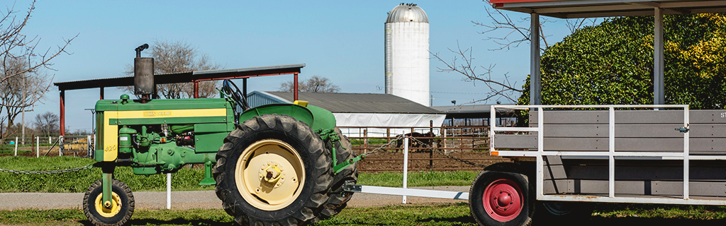 A tractor sits in front of a farm buliding