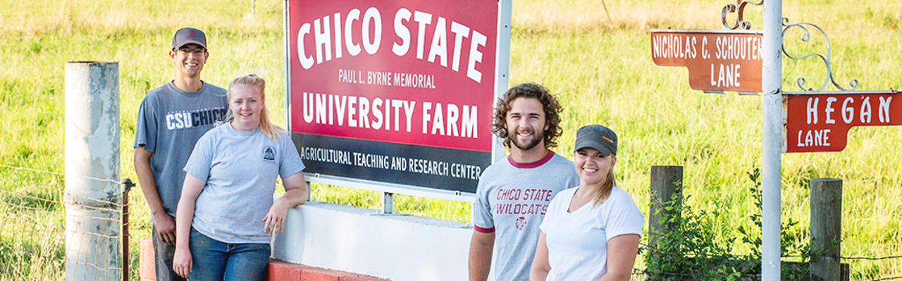 Four students stand by the entrance to the University Farm