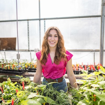Student standing in greenhouse. 