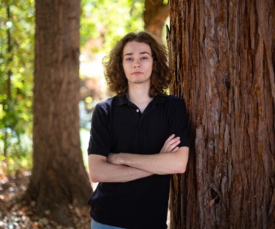 Student standing next to tree. 