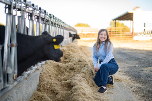 Student standing next to cows. 