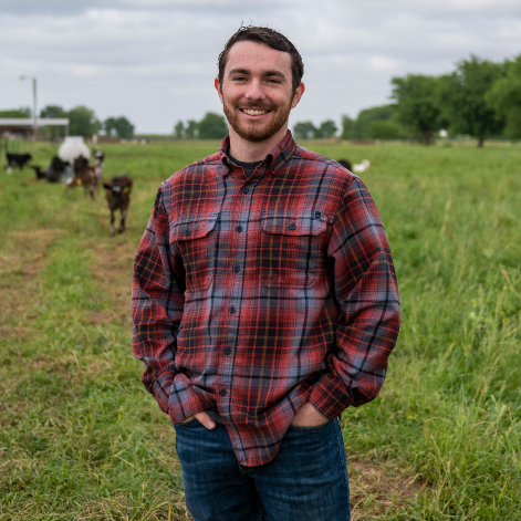 josh roter stands in dairy pasture