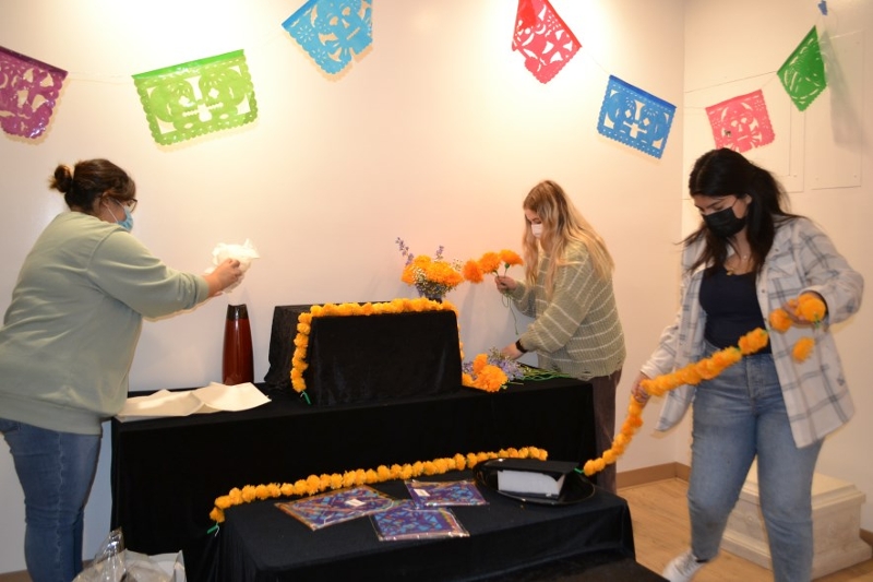 Students at the museum help with setting up the altar in the museum lobby in honor of Day of the Dead Dia De Los Muertos