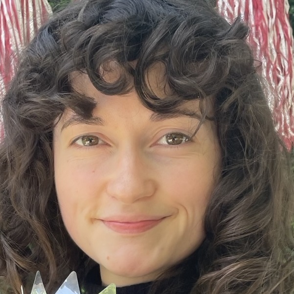 Close-up headshot of Dani Mouly with short curly brown hair and brown eyes
