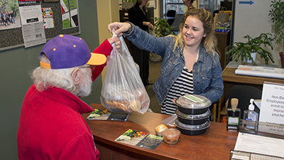 Student hands bag of food to elderly man
