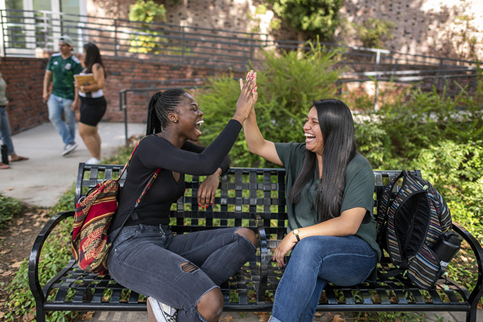 Two girls sitting on a bench high-fiving
