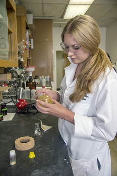 female student with white lab coat using chemistry equipment