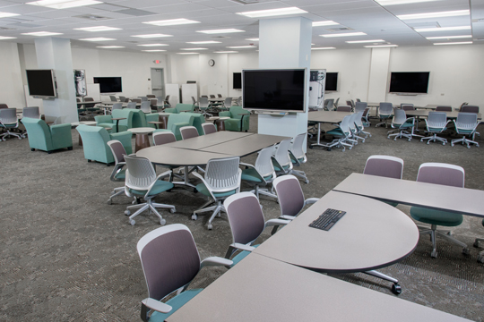 Rolling chairs surround tables equipped with individual screens for sharing in THMA 116