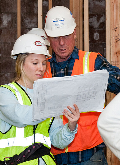 student with hard hat looking over plans with instructor