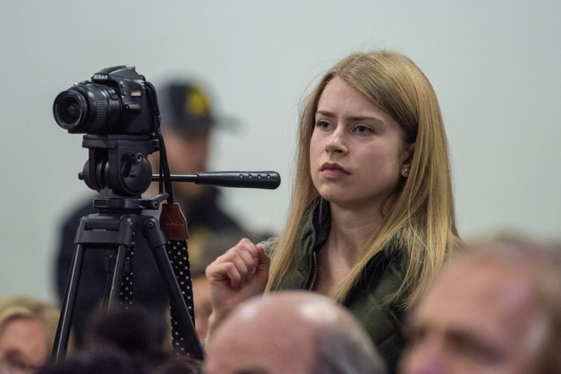A student reporter next to her camera is taking notes during a press conference