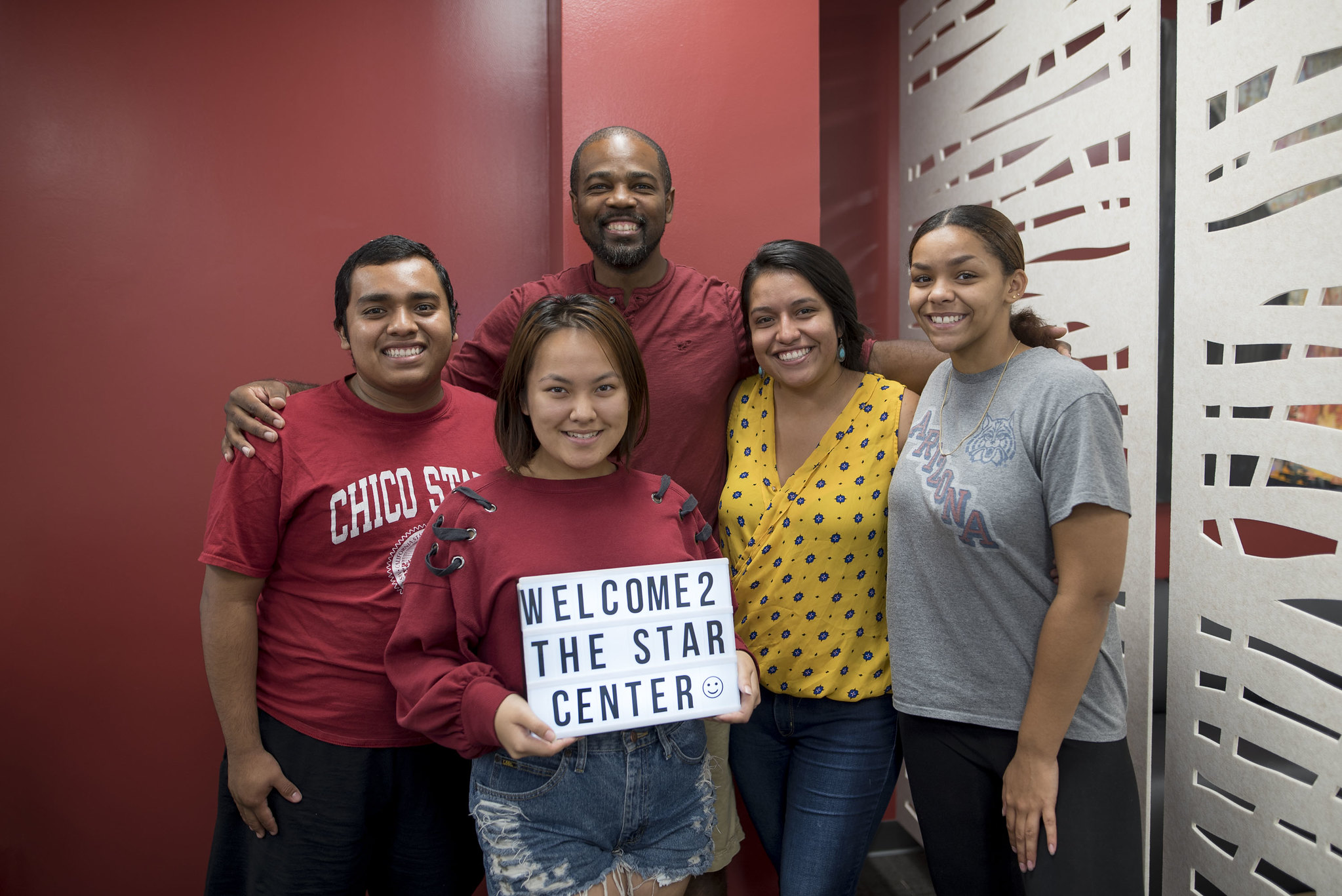 Several peer advisors smile while holding a welcome sign