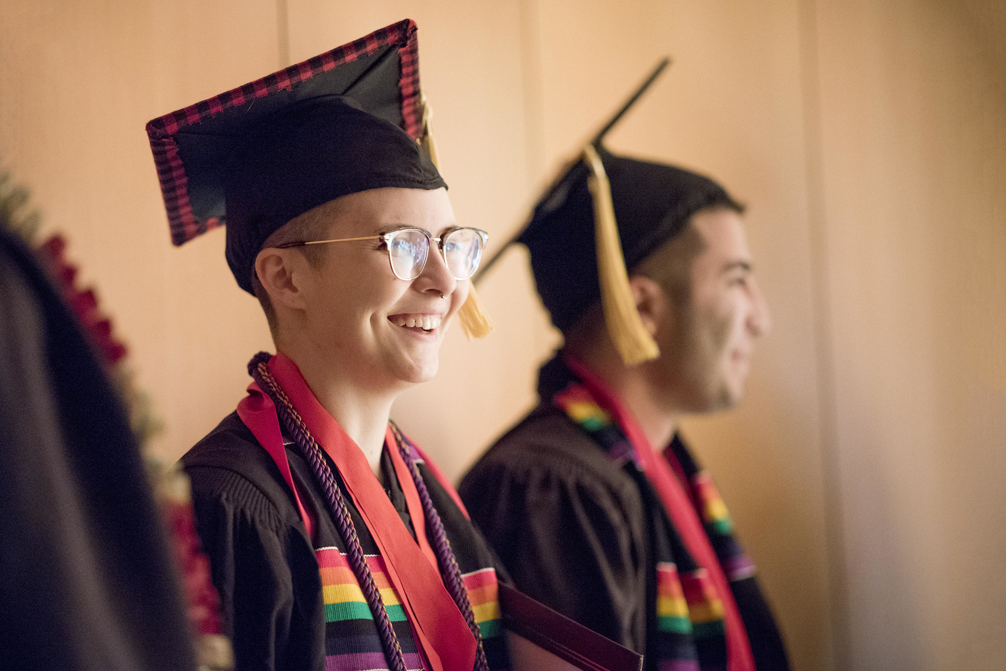 Two students wearing academic robes smile