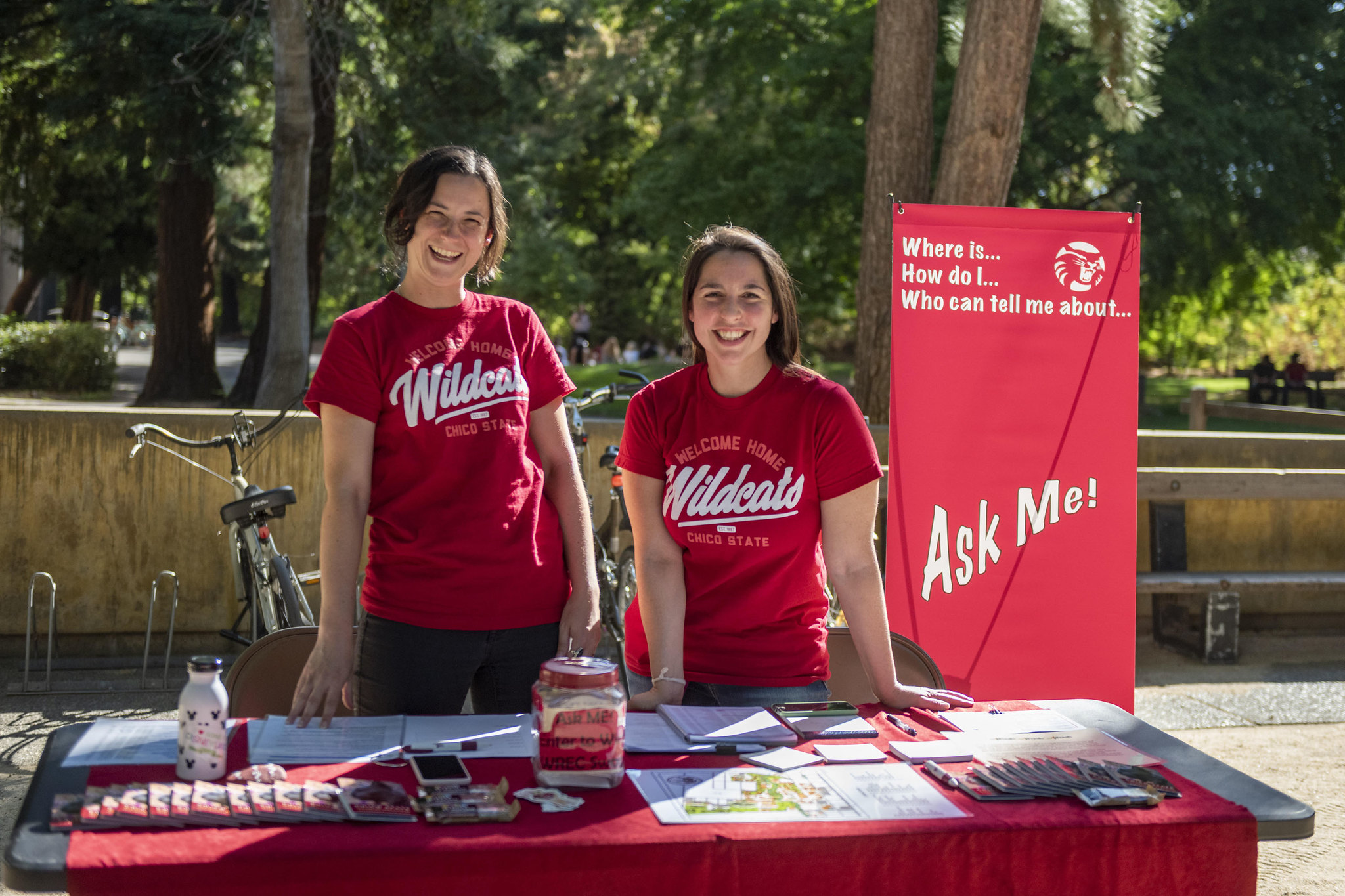 Two people stand at the Ask Me table, smiling