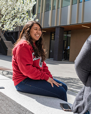 Student Smiling while sitting in front of the Arts and Humanities Building
