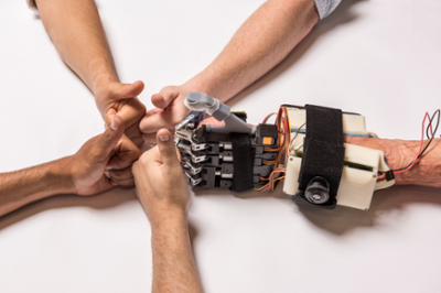 Albertito Salomon (right) reaches out with his new hand to Brett Smith, Douglas Smith, William Cortez, and Peter Matulich (clockwise from right) who were all part of a senior-level engineering students on Tito's Left Hand team create a mechanical hand solution as part of the Capstone Design Program on Friday, May 13, 2016 in Chico, Calif. (Jason Halley/University Photographer)