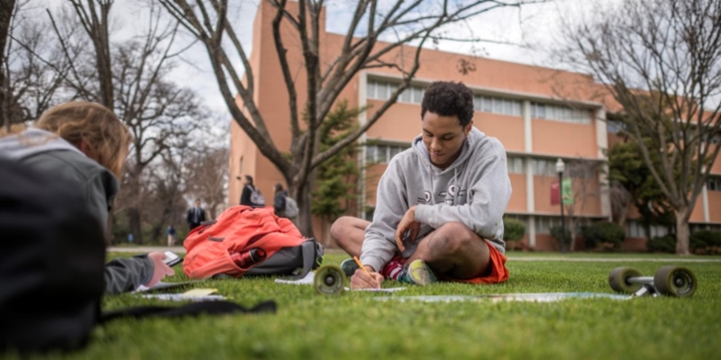 A student studies on the lawn outside Glenn Hall.