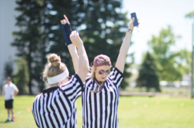 Student wearing a referee outfit whistling at a student organization event.