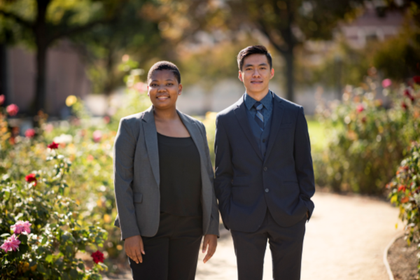 Two students pose for a photo in their professional attire.