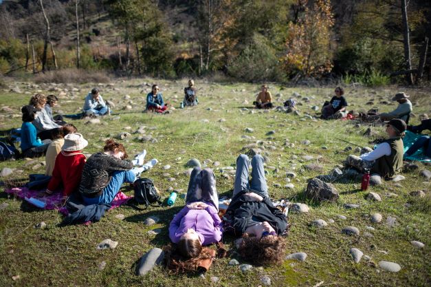 Students laying in a circle in nature.