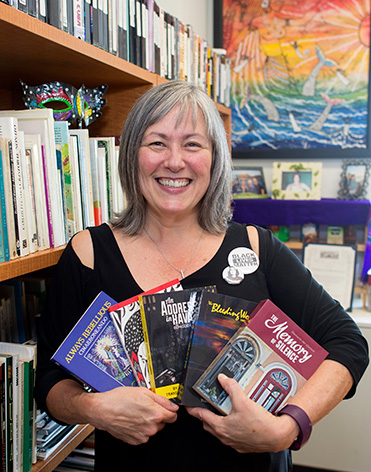 Spanish Professor Sara E. Cooper is photographed in her office holding a collection of Cubanabooks