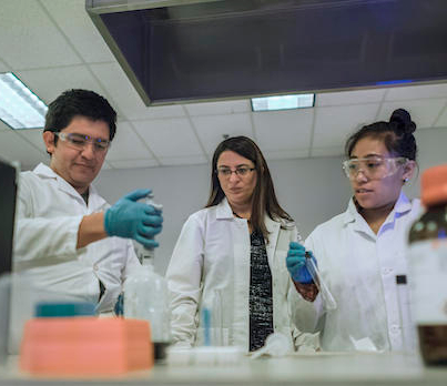 three students in a lab coat in a lab environment