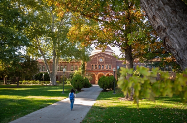 A person in the distance walking towards Kendall Hall, the main administration building at Chico State. 