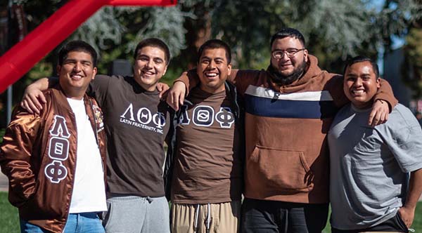 Latino fraternity members smile at a club recruitment event