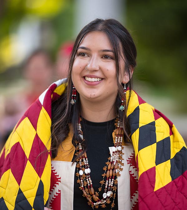 Native American student wearing necklace and blanket at Native American grad celebration